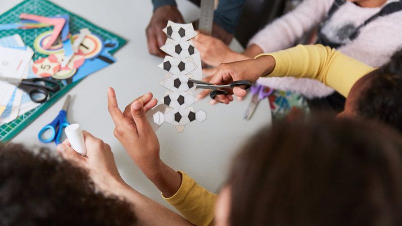 A little girl cutting out a template to make a papercraft football.
