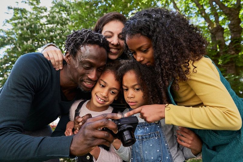 A family gathered around a camera, looking at images.