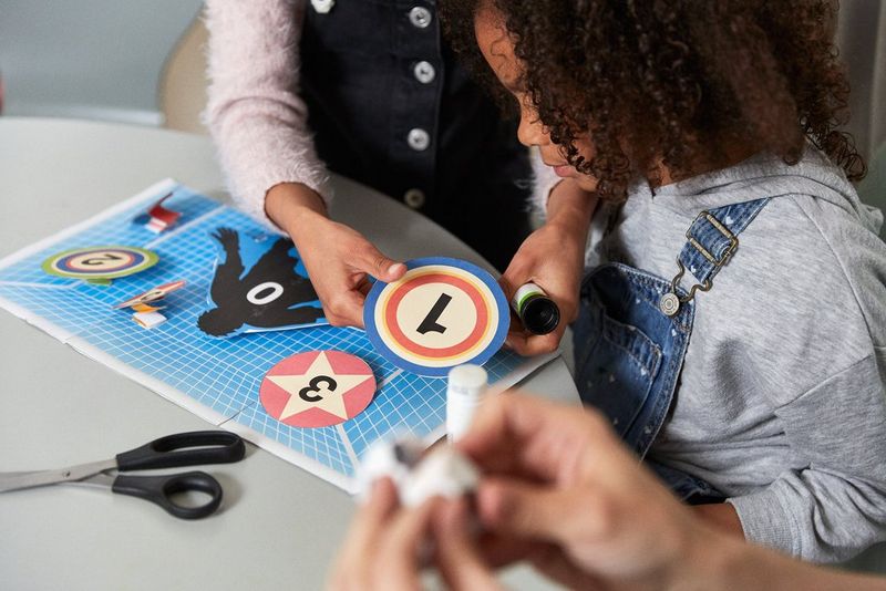 Two girls gluing targets on a paper football goal.