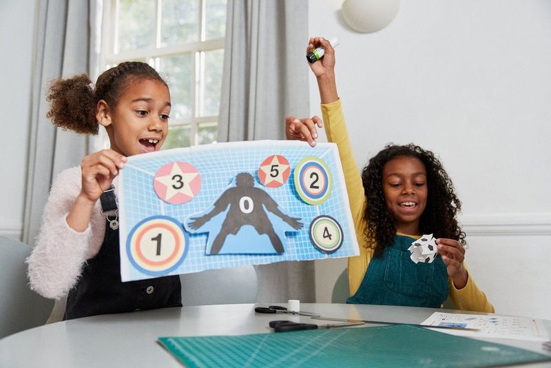 Two girls showing off their football papercraft creations. 