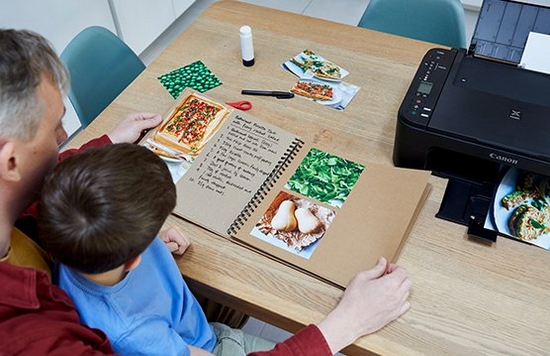 A father and son flick through the pages of a homemade recipe book.