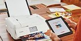 A tablet displays the Canon Easy-PhotoPrint App while a printer prints a picture.