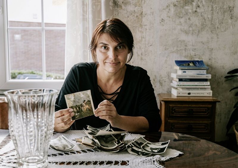 A woman sitting at a table holding a water-damaged photo.