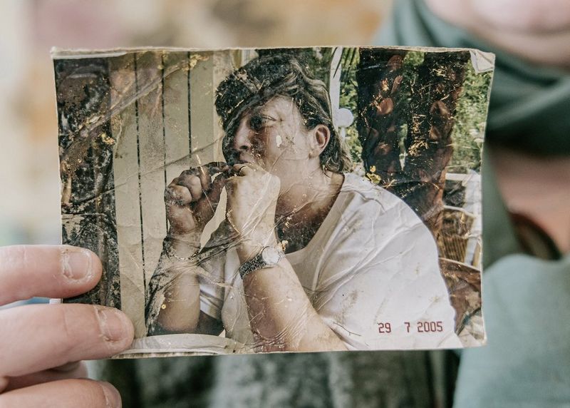 A creased, water-damaged photograph of a woman eating.