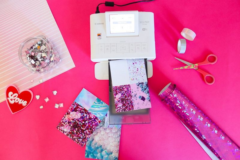 A Canon SELPHY CP1300 printer printing out a sheet of paper with four different sparkly patterns on it.