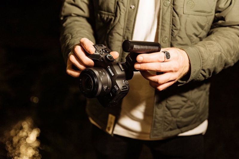 A man fits a microphone to the Multi-function shoe on top of a Canon EOS R6 Mark II camera.