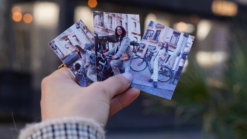 A hand holding three images, printed on a Canon Zoemini 2 instant printer, of a woman wearing different outfits.  