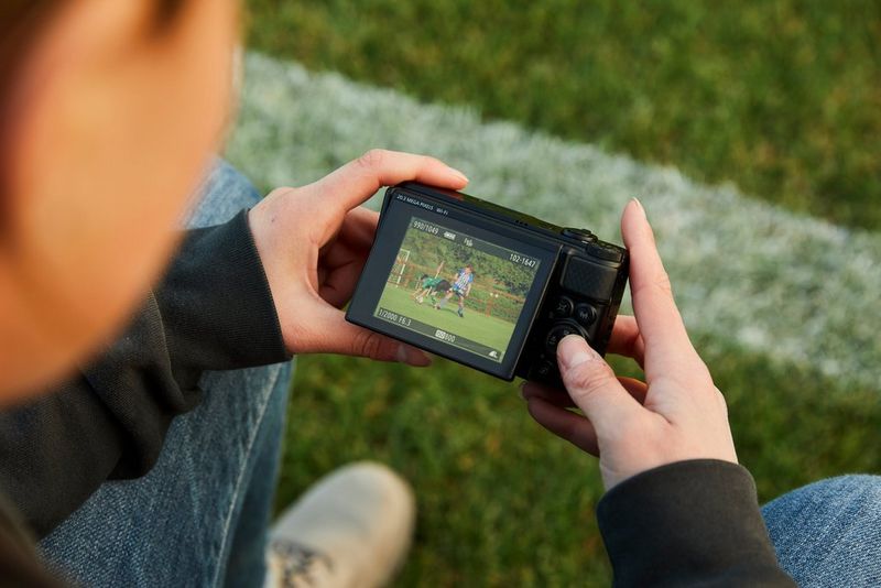 A person looking at an image on the flip-up screen of a Canon PowerShot SX740 HS.