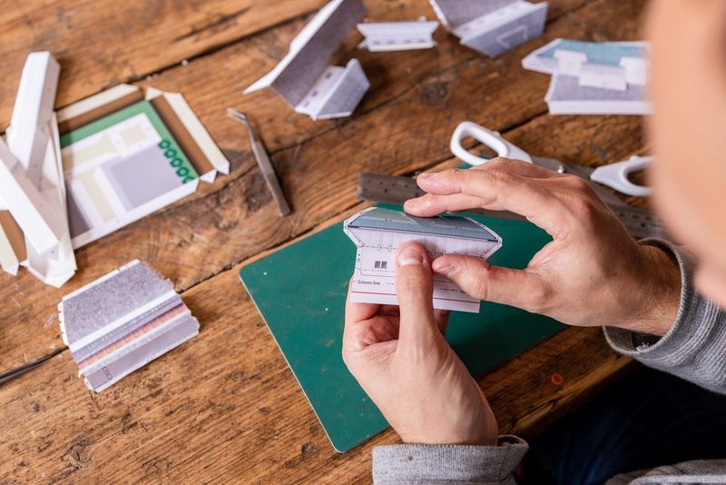 Hands using a ruler and a pair of scissors to cut out part of a Canon Creative Park template.