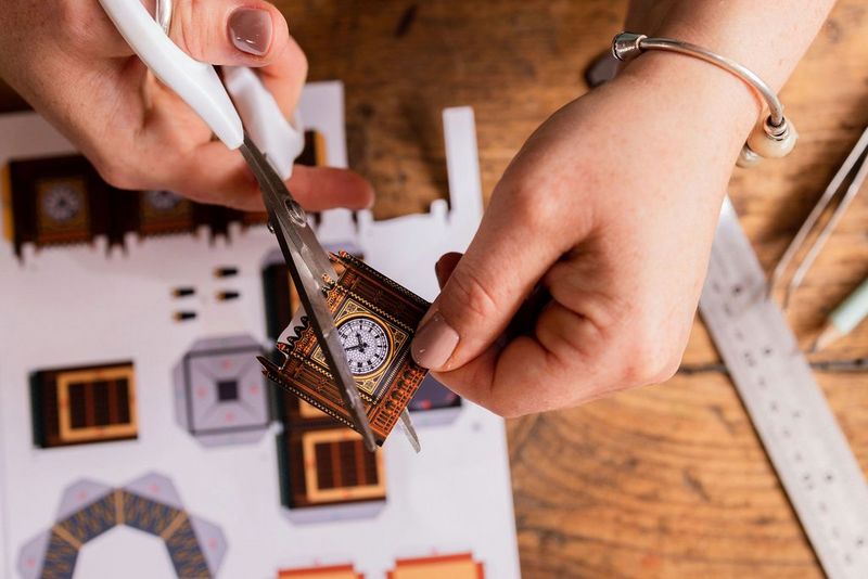 Hands using scissors to cut out parts from a Canon Creative Park template of Big Ben printed on Canon Matte Photo Paper.
