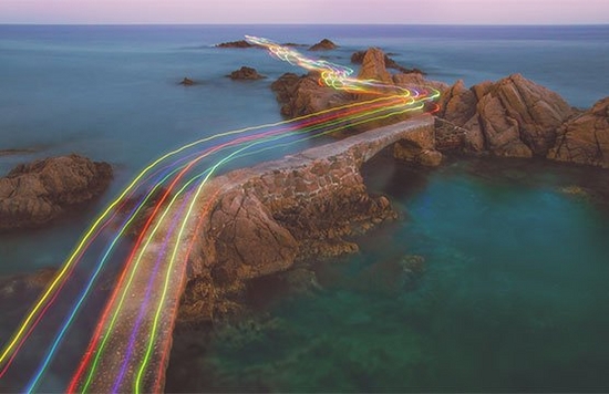 Colourful light beams running over the top of a coastal footpath.