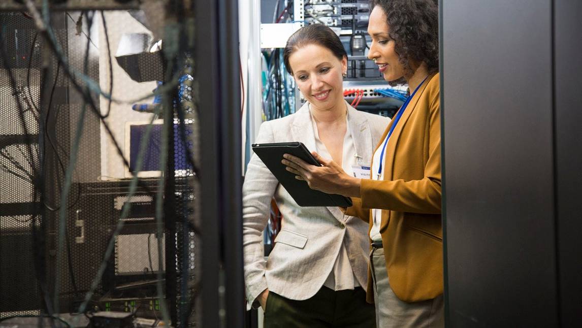 Two female office employees talking in a server room