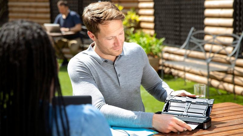 An image of a man looking at a portable scanner outside