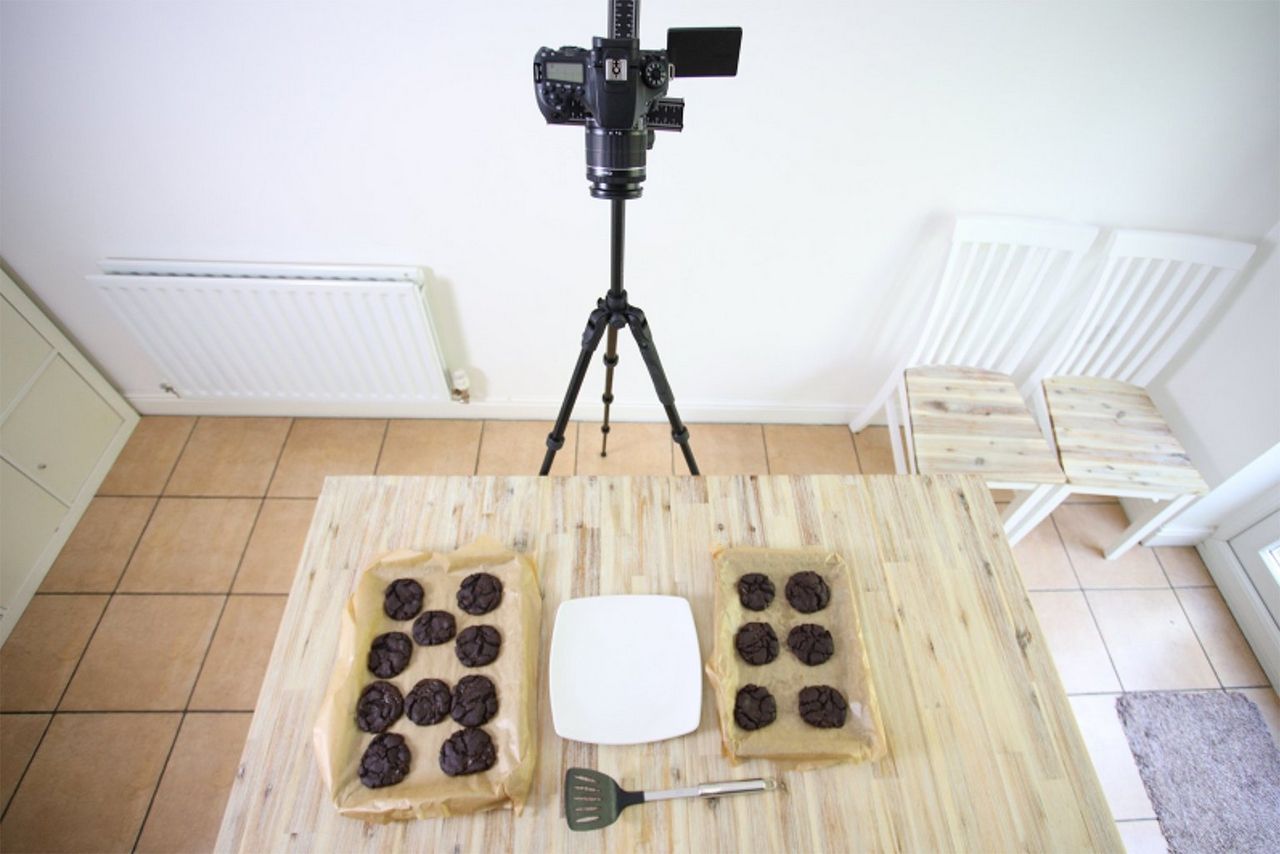A Canon EOS 90D on a tripod filming cookies cooling on trays.
