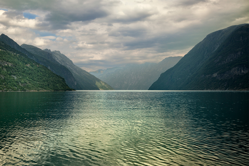 Green mountain hills reflecting in the surface of water.