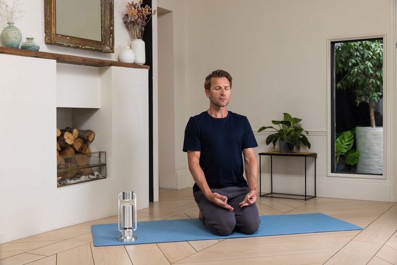 A person kneels on a yoga mat next to a Canon Light & Speaker ML-A.