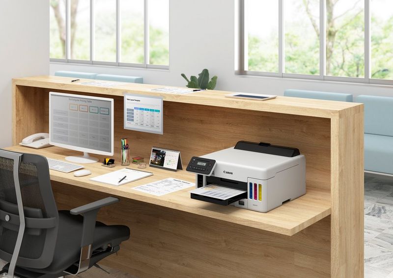 The MAXIFY GX5050 printer on a neatly organised office desk with stationery, a monitor, keyboard and phone.