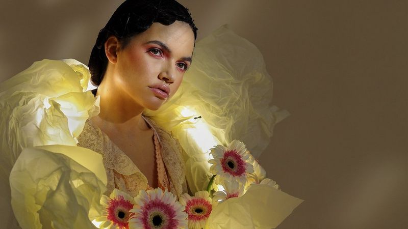 A woman wearing a yellow dress and garlanded with flowers, captured by the Canon RF 35mm F1.8 MACRO IS STM.