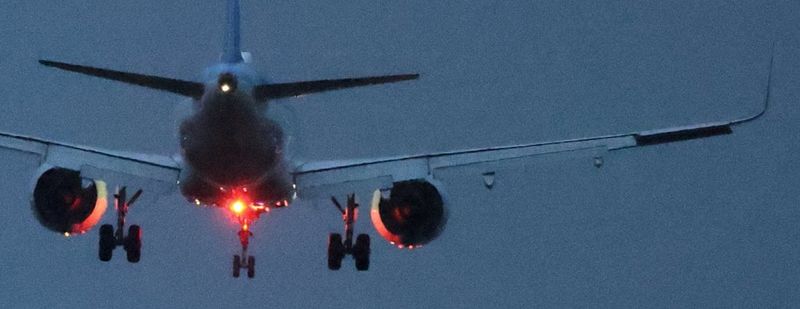 Detail of an image shot in low light at high ISO of an aircraft flying against a dark blue sky, appearing very grainy and noisy. 