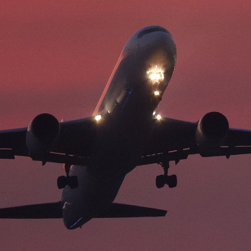The same image of an aircraft in flight against a red sky, looking cleaner after processing using image.canon's Cloud RAW image processing.