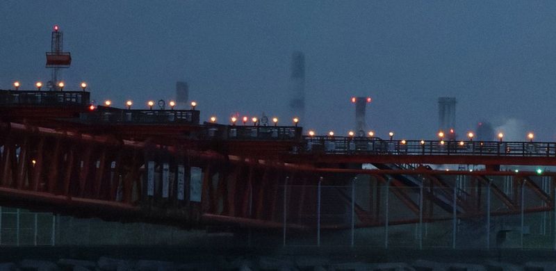 Detail from an image taken in low light at high ISO showing airport landing lights on elevated structures against a dark blue sky, after processing by image.canon, with less image grain and noise. 