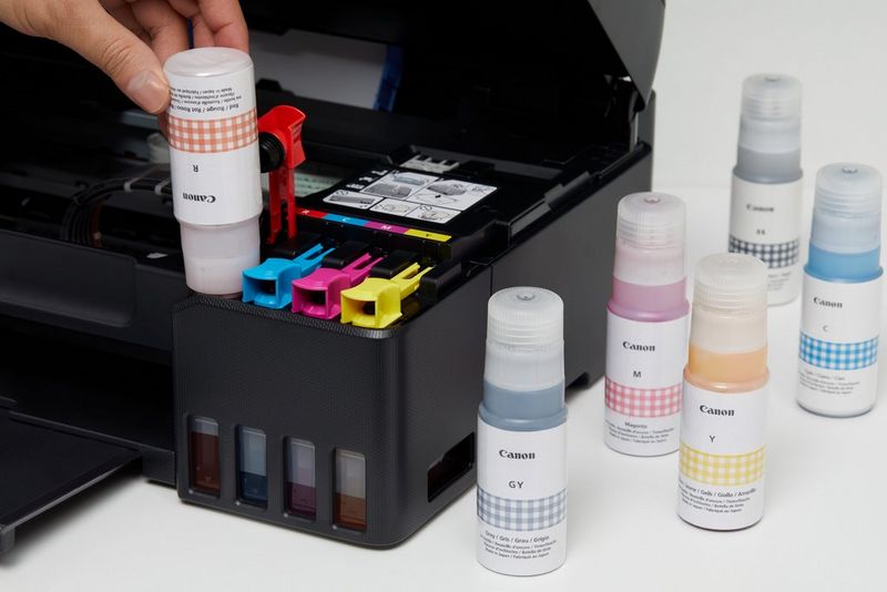 MegaTank ink bottles being installed in a Canon PIXMA printer.