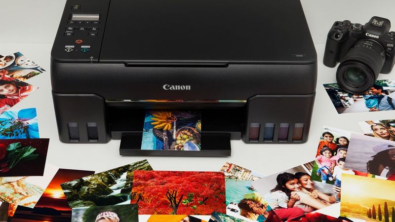 A Canon PIXMA printer with a Canon camera next to it, and a selection of travel, food and portrait prints laid out around it.