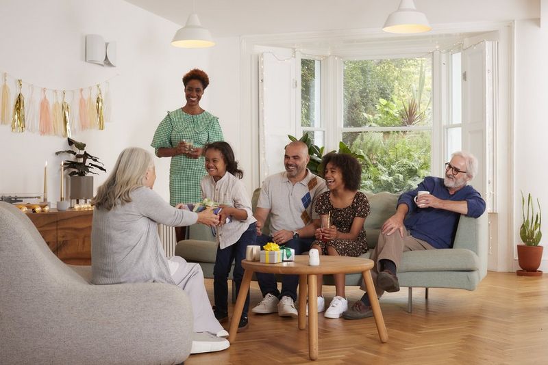 A seated older woman hands a present to an excited young child. A Canon PowerShot PX is on the table next to them, capturing the smiling group.
