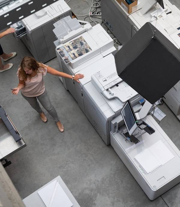 Woman standing next to a large printer