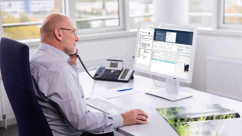 Work professional in the office working at his computer and talking on the phone