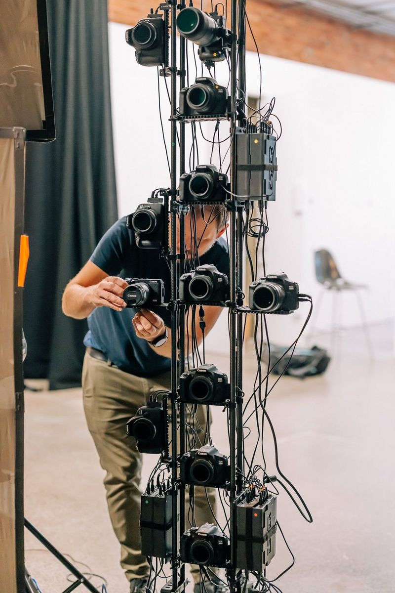 A technician adjusts one of the Canon cameras in a tall camera array.