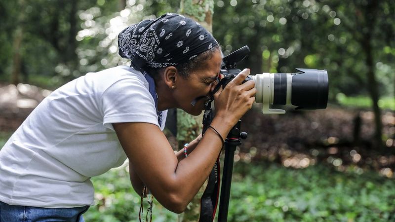 Aïda Muluneh leans forward to look through a Canon camera, taken by Ben Saïd Sangaré.