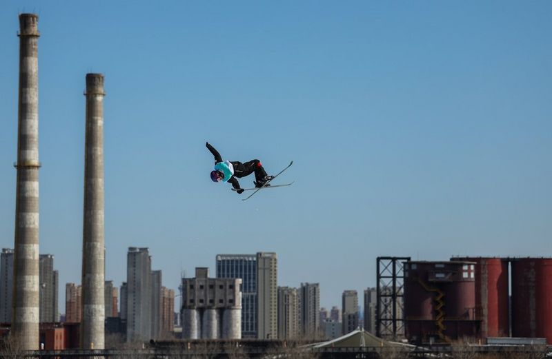 A skier is captured mid-air against the rooftops of a cityscapes. Taken on a Canon EOS R3 with a Canon RF 70-200mm F2.8L IS USM lens.
