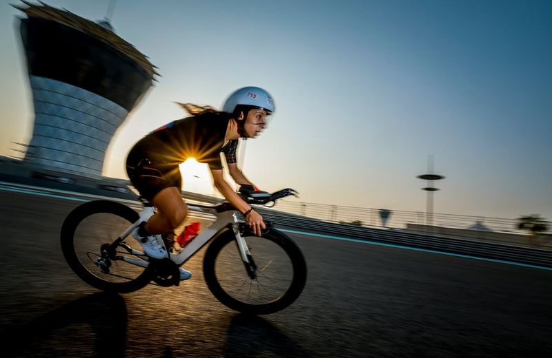 A cyclist is captured at speed, the sunshine emerging through an out of focus background. Taken on a Canon EOS R3 with a Canon RF 15-35mm F2.8L IS USM lens.