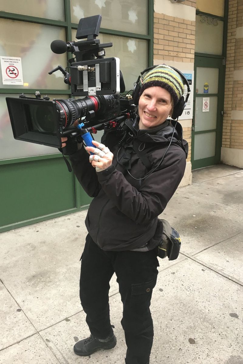 Cinematographer Laela Kilbourn photographed on an urban street with a camera rig on her shoulder.