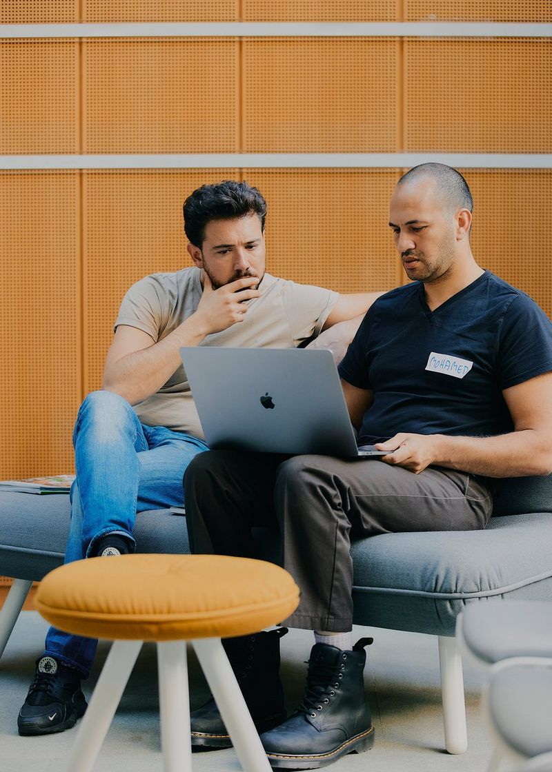 Photojournalist Mohamed Hassan sits with another man at the Canon Student Development Programme, both looking at a laptop screen.
