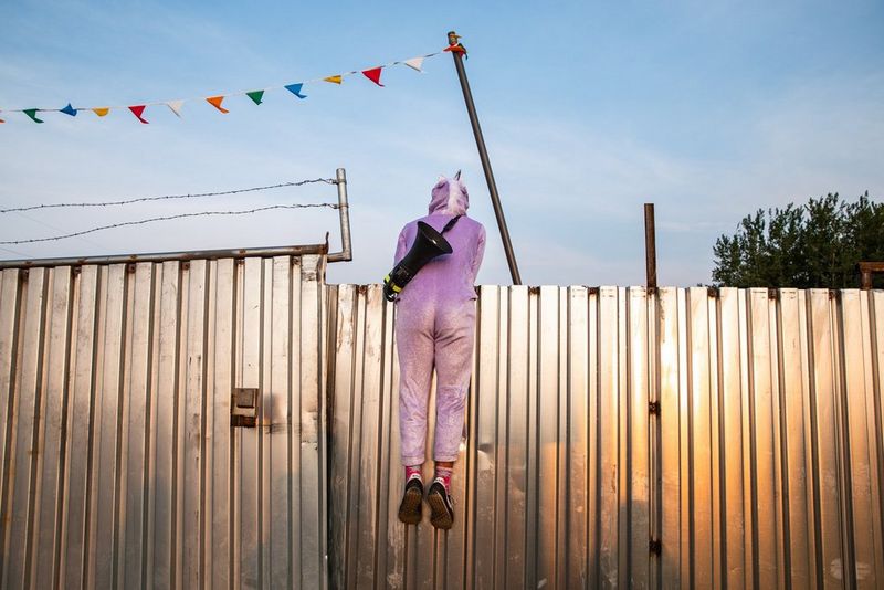 A photo taken by Canon Student Development Programme participant Chris Trinh of a person in a unicorn costume and with a megaphone slung over their shoulder hanging from a steel fence.