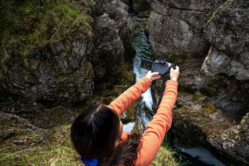 Photographer Ulla Lohmann holds an EOS R5 at arm's length over a precipice and frames her shot on the vari-angle screen.