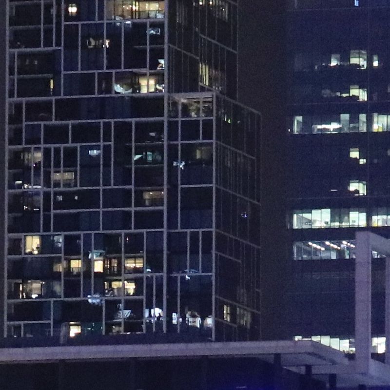Two office buildings at night, with lights on in the windows.