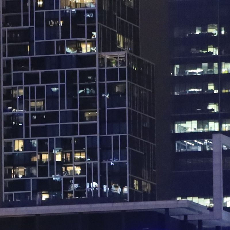 Two office buildings at night, with lights on in the windows.