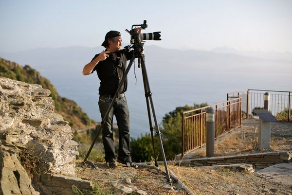 Sébastien Devaud working on location, positioning his Canon kit on a tripod by the coast.