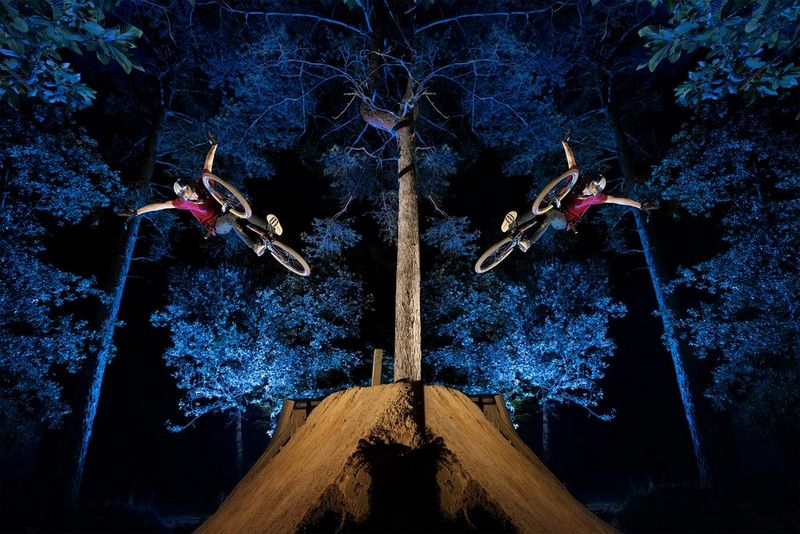 A mirror image of a rider making a daring leap with his arms held aloft. The forest background is bathed in blue light.