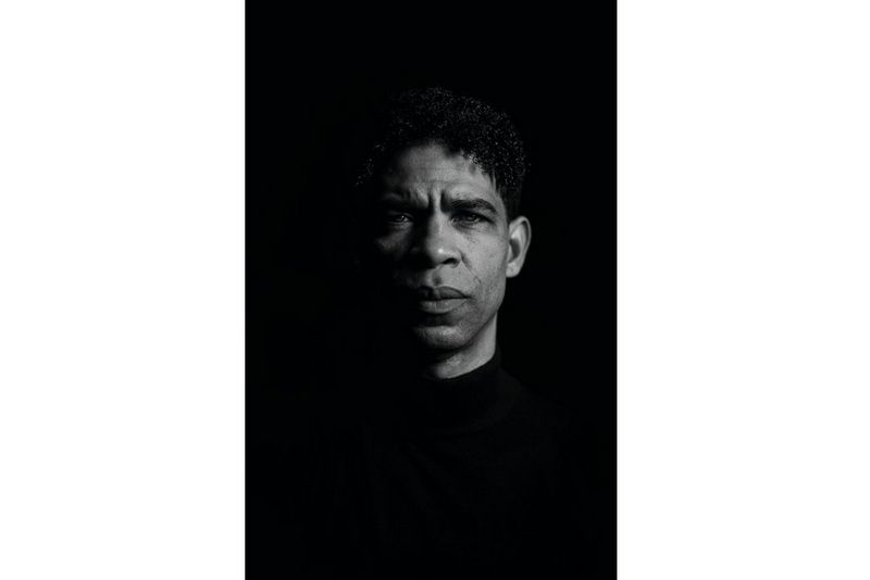 A black and white portrait of a man staring directly at the camera.