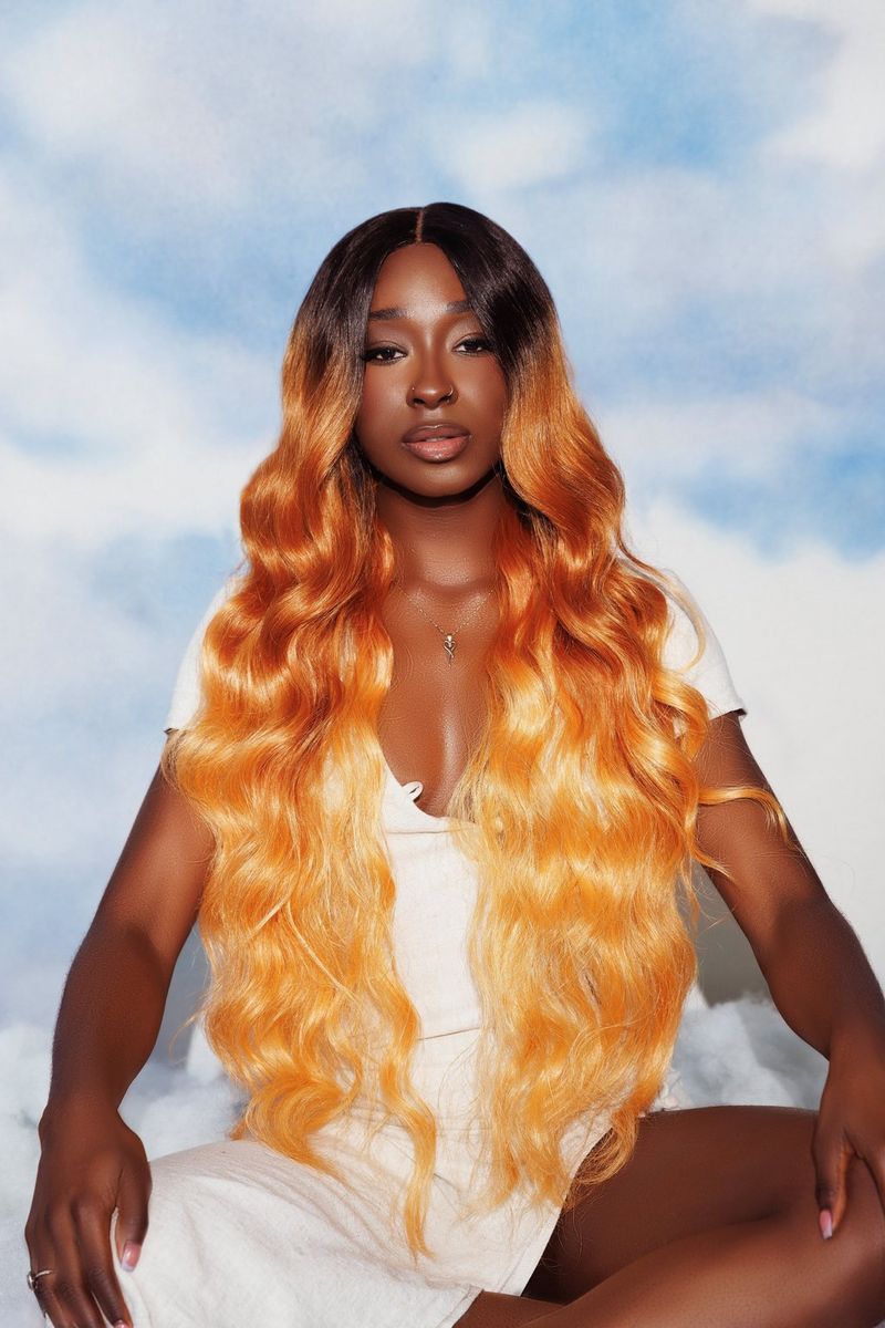A portrait of a model with long yellow-orange hair wearing a white dress, taken by Jade Keshia Gordon. 