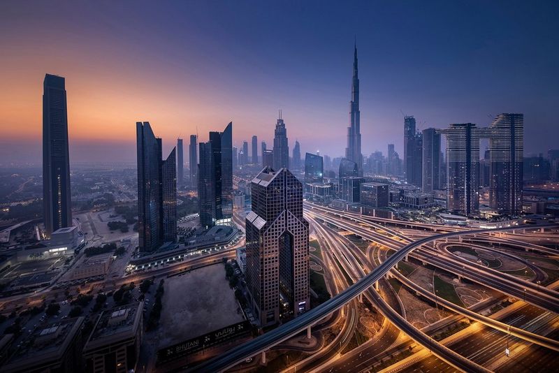 Dubai at night with the Burj Khalifa tower prominent against a moody sky.