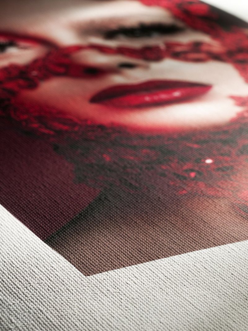 A close-up of the corner of a photo print on heavily textured paper, showing a pale woman's face wearing bright red lipstick.