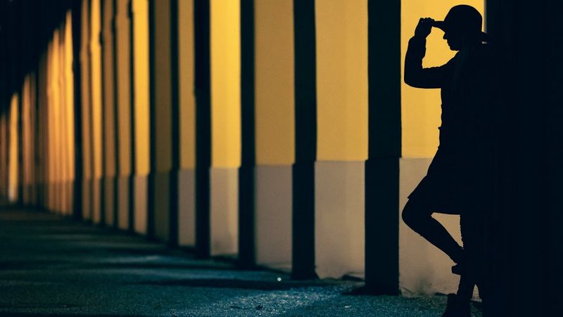 A figure in silhouette leaning against a building illuminated with yellow light. Taken by Canon Ambassador Lorenz Holder on a Canon EOS R6.