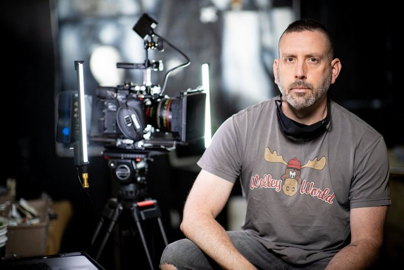 Filmmaker Alan Griswold sitting beside a Canon Cinema EOS camera on a tripod.