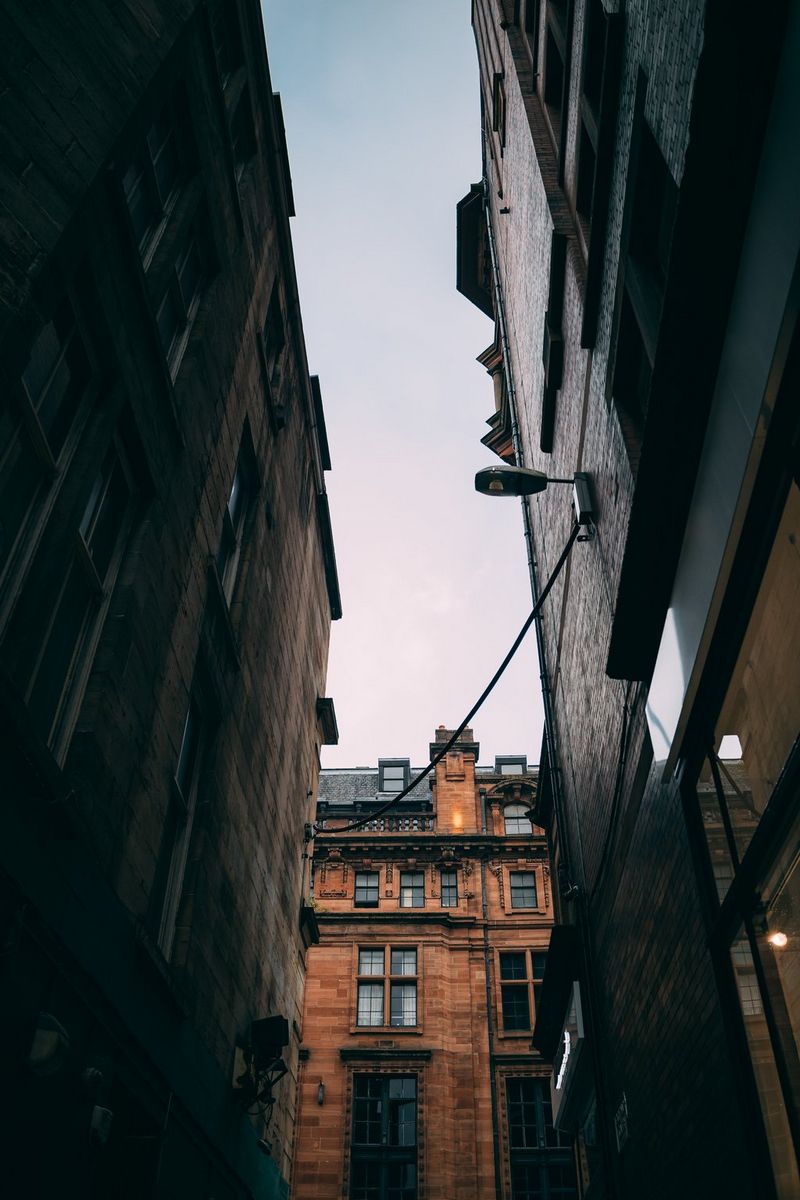 Two ornate buildings in shadow frame a third building bathed in sunlight in this street photograph taken from below. 