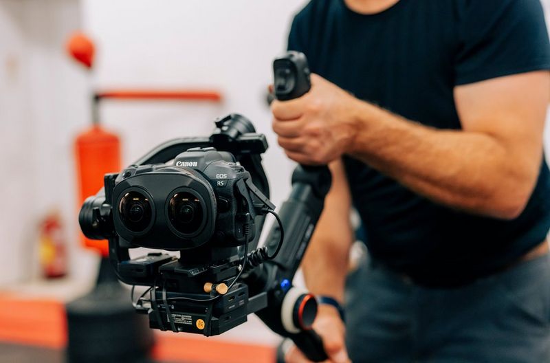 A person using a Canon EOS R5 camera with a Canon RF 5.2mm F2.8L Dual Fisheye lens.